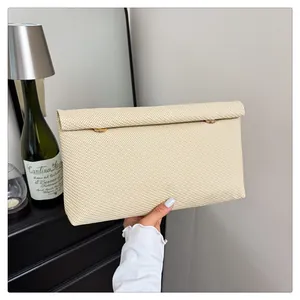 Gros plan d'une pochette beige tissée avec des fermoirs cylindriques dorés élégants