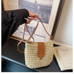 Detail van geweven bucket bag van papierkoord met bruine leren riem en metalen gesp