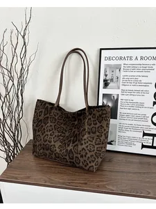 Détail d'un sac cabas en peluche léopard avec des anses marron sur bois