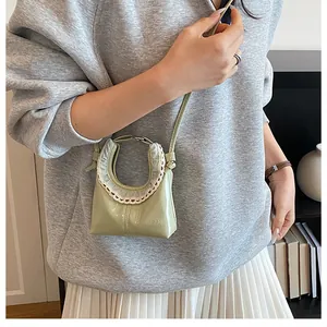 Detail of avocado green mini bag with white lace trim and round metallic handle