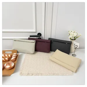 Gros plan de quatre pochettes enveloppes colorées avec texture tissée et boucle en métal