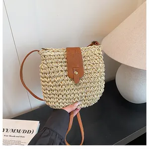 Detail van de geweven stro emmer tas met bruine lederen riem en gouden metalen gesp
