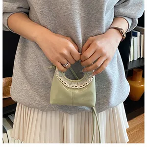 Close-up of light green mini half-moon bag featuring white lace trim and logo detail