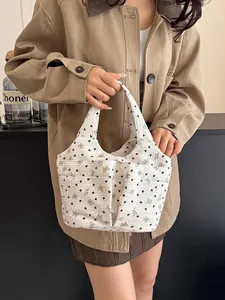 Elegante borsa a mano floreale con fiocchi marroni e tessuto trapuntato tenuta in mano