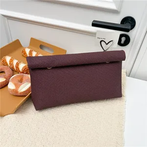 Pochette minimaliste en tricot violet foncé avec texture tissée sur tapis à franges