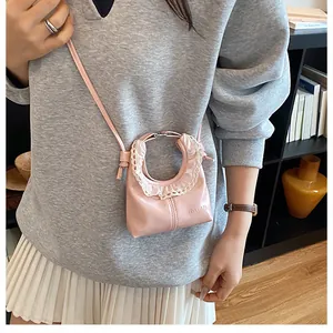 Close-up of pink crescent mini bag with white lace trim and embossed logo detail