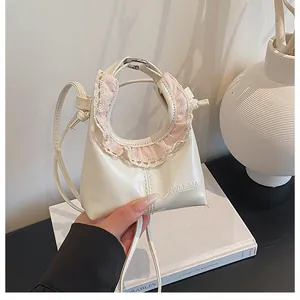Close-up of cream mini crossbody bag with pink lace trim and brand logo details
