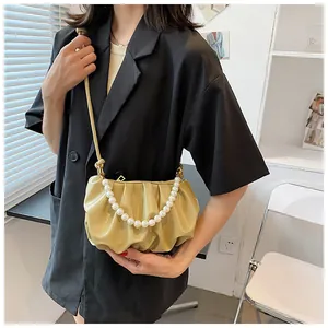 Dettaglio della borsa a nuvola beige con catena di perle e tracolla in pelle