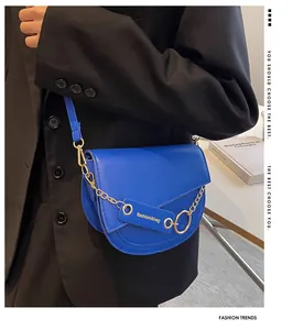 Dettaglio borsa a sella blu con catena dorata e texture liscia in ecopelle di lusso