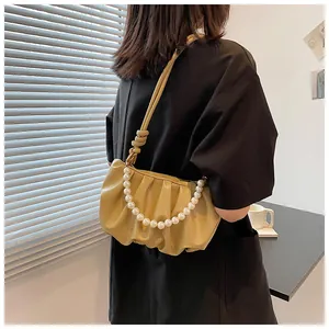 Vista dettagliata della borsa cloud a pieghe beige con grandi perle bianche decorative