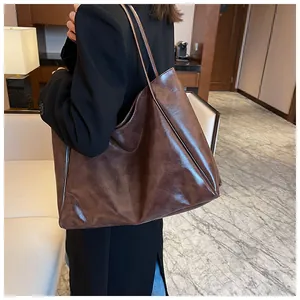 Détail du grand sac cabas marron foncé à texture cuir huilé porté par un mannequin