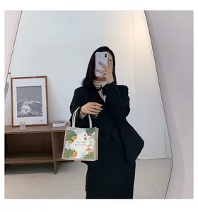 Mirror selfie showing a small linen tote bag with pumpkin and palm leaf prints