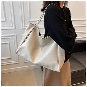 Gros plan d'un sac cabas minimaliste en cuir crème porté en bandoulière pour femme