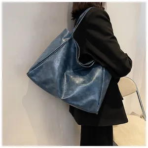 Grand sac cabas gris bleu en cuir huilé porté par un mannequin en gros plan