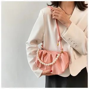 Dettaglio della borsa a nuvola rosa con manico di perle bianche e tracolla in pelle