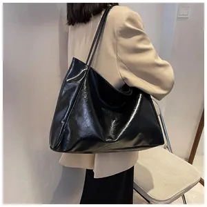 Gros plan sur la texture du cuir noir brillant et les coutures de la bandoulière du sac