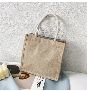 Dettaglio ravvicinato di una borsa in juta con manici in corda bianca e fodera interna blu