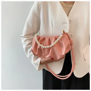 Dettaglio della borsa a pieghe rosa con manico di perle e tracolla in pelle