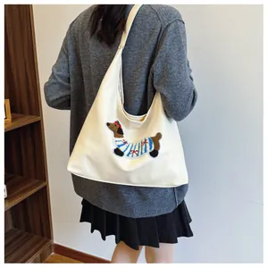 Dettaglio della borsa hobo crema con ricamo a forma di bassotto per un look quotidiano