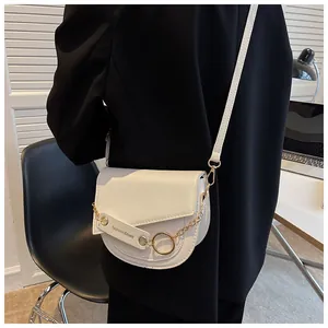 Borsa a sella bianco crema con catena d'oro indossata su una giacca nera elegante