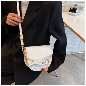 Dettaglio della borsa a sella bianca con catena dorata e targhetta fashion elegante