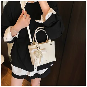 Detailed shot of beige crossbody bucket bag with pearl heart charm and lace bow decor