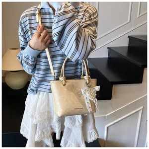 Close-up of champagne small tote bag with pleat texture and heart lace pendant