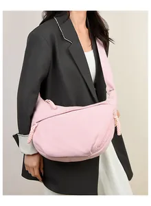 Pink corduroy crescent bag shown on model highlighting the vertical rib texture and strap