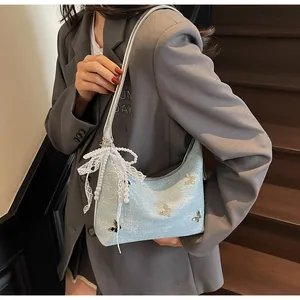 Detail of light blue glitter shoulder bag with silver butterfly and lace pearl charm