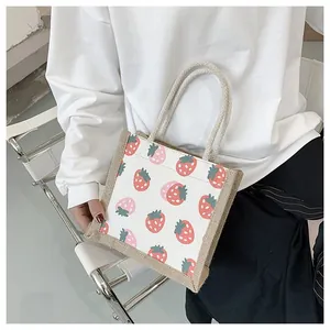 Detail of strawberry printed canvas tote bag with textured jute handles for daily use