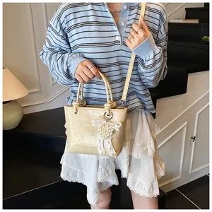 Detail of cream white PU handbag with lace bow, pearl heart charm and crossbody strap