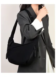 Detail of black corduroy crescent bag with textured fabric and braided zipper puller