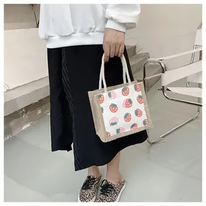 Close-up of strawberry print canvas tote bag with white rope handles in a modern setting