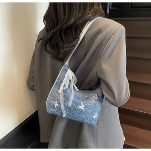 Blue denim half-moon bag with silver butterfly charms and pearl lace details on model