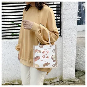 Detail of canvas tote bag with bread print and knotted handle in a casual street setting