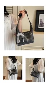 Detail of grey shoulder bag with silver butterflies and white lace bow with pearls