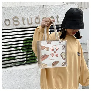 Close-up of linen tote bag with bread illustration and cotton rope handle outdoors