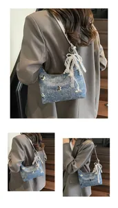 Detail of denim texture hobo bag with butterfly embroidery and lace pearl pendant