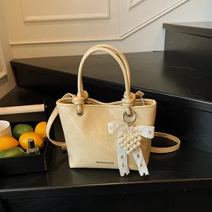 Cream yellow square handbag with pleated texture and lace pearl charm on wooden stairs