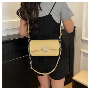 Detail of yellow lychee grain leather bag with silver buckle and metal chain strap