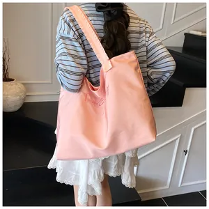 Close-up of pink canvas tote bag with embroidery details on a wide shoulder strap