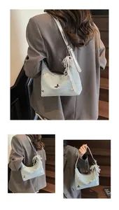 Detail of light blue shoulder bag with butterfly embroidery and pearl lace charm