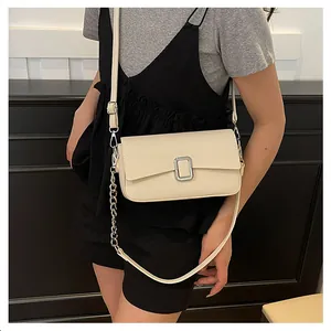 Close-up of cream leather shoulder bag with lychee texture and silver metal buckle
