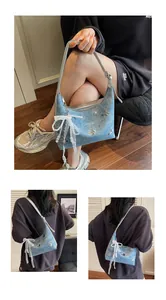 Detail view of light blue denim hobo bag with silver butterfly patches and lace bow