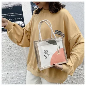 Mini linen canvas tote bag with orange print and rope handles held by a model