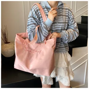 Detailed view of pink tote bag with 'I am Creamy' embroidery on nylon fabric
