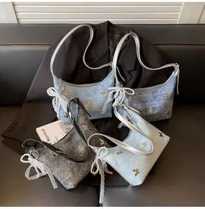 Close-up of denim shoulder bags in blue and grey with butterfly sequins and pearl charms