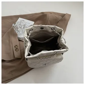 Interior view of quilted chain bag showing brown fabric lining and zip pocket detail