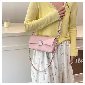 Detail of pink crossbody bag with silver buckle and chain strap on a floral skirt outfit