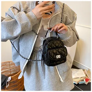 Detalle de mini mochila negra acolchada con correas de cadena plateada y cierre giratorio